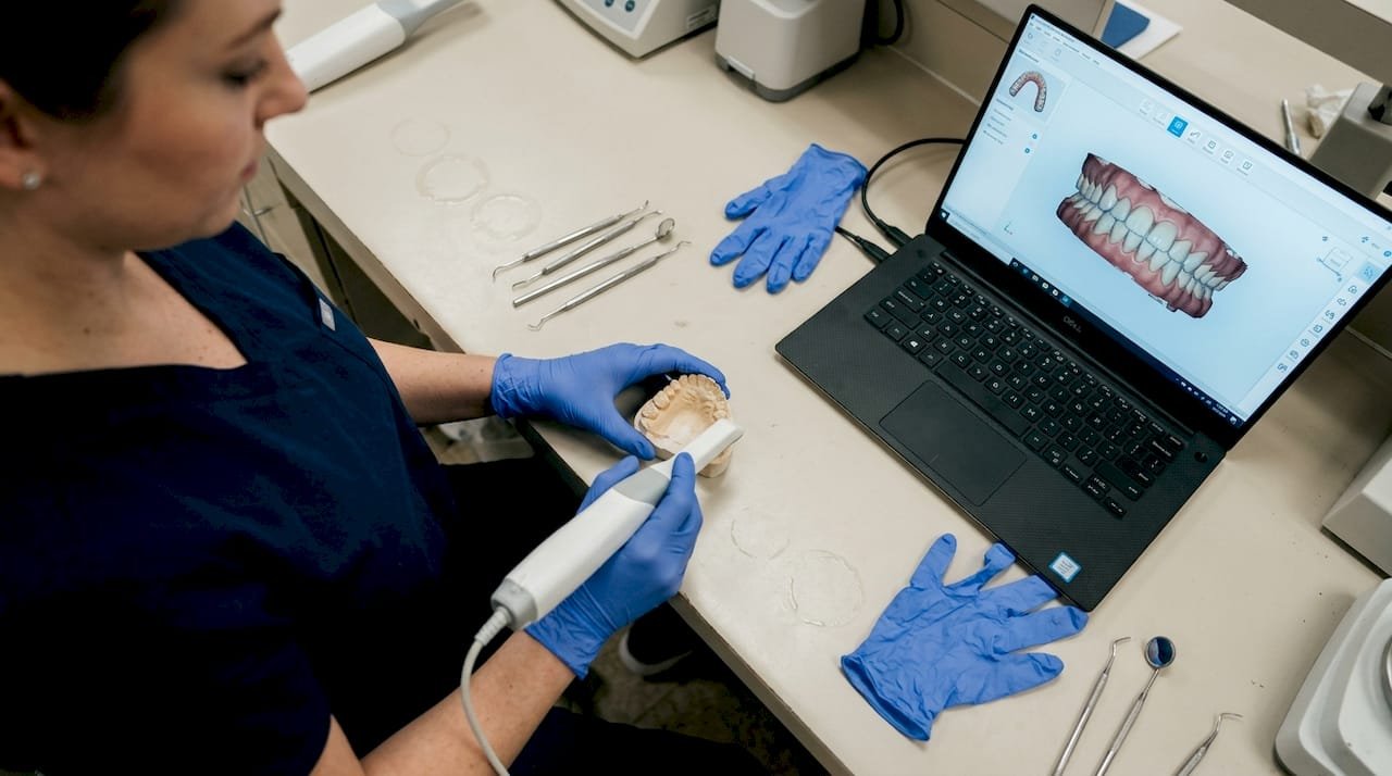 Eine zahnmedizinische Assistenz scannt ein Zahnmodell mit einem 3D-Scanner ein.