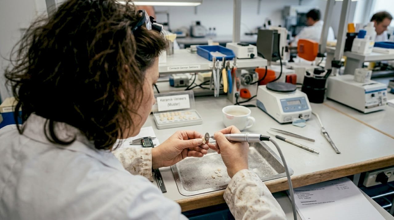 Im Labor bringt ein Zahntechniker eine Keramikveneers zum Glänzen.